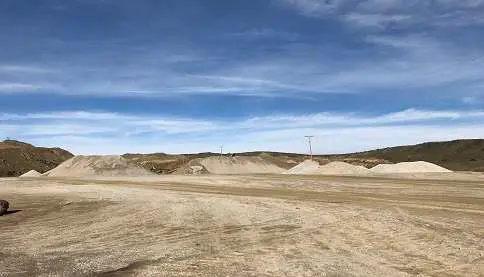 Expansive dirt landscape with small hills and a clear blue sky, likely a construction or excavation site. Highlights open terrain suitable for industrial, construction, or development projects.